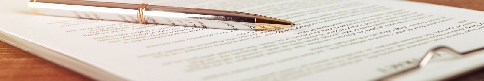 There is a silver and gold pen sitting on top of a document in a clipboard.