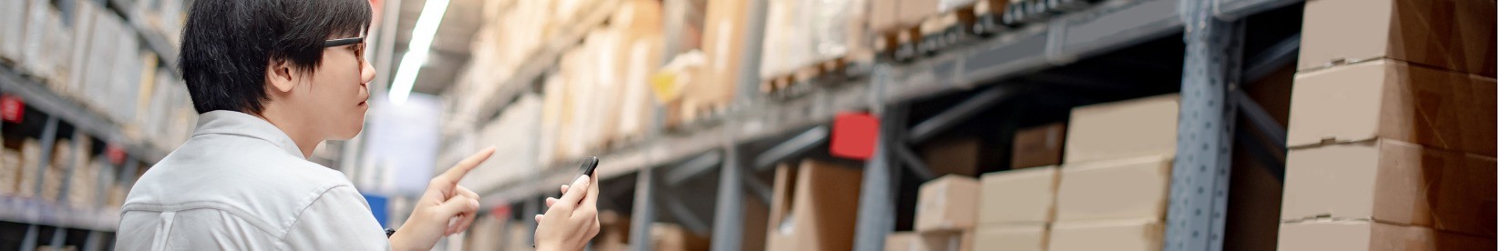 Man shopping for goods with a mobile device in a warehouse. 