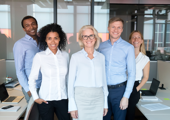 A group of five business people smile at the camera.