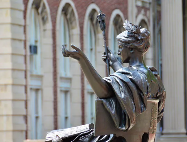 View of statue of Alma Mater from the side, with buildings behind.